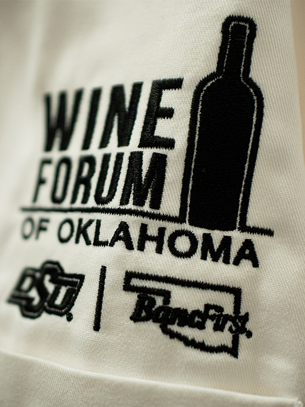 A closeup photo of the Wine Forum logo on a chef's jacket.
