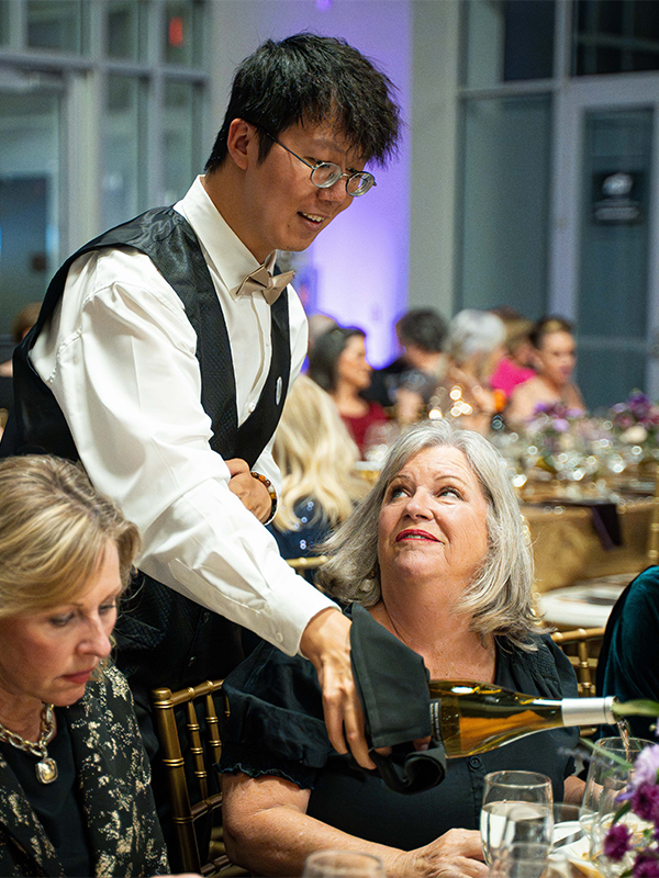 A student waiter laughs with a patron of the Wine Forum